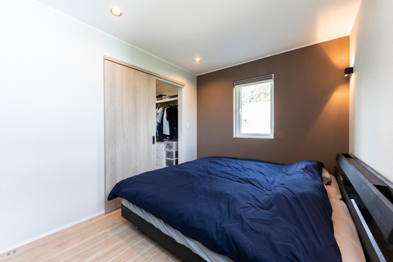 寝室、ウォークインクローゼット：ブラウンのアクセントクロスで落ち着いた雰囲気の寝室
